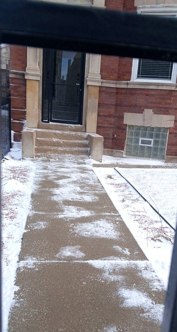 Treated walkway leading to a building entrance, surface wet and clear